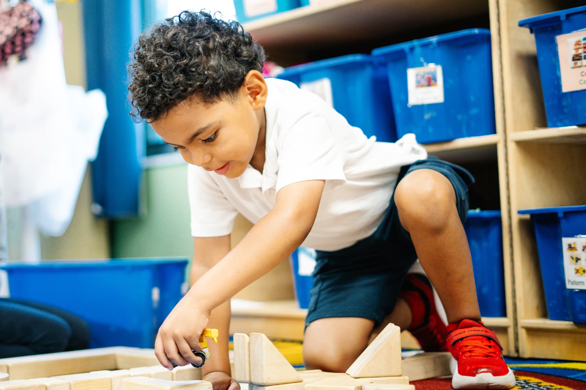 Student building with wooden blocks in a preschool classroom