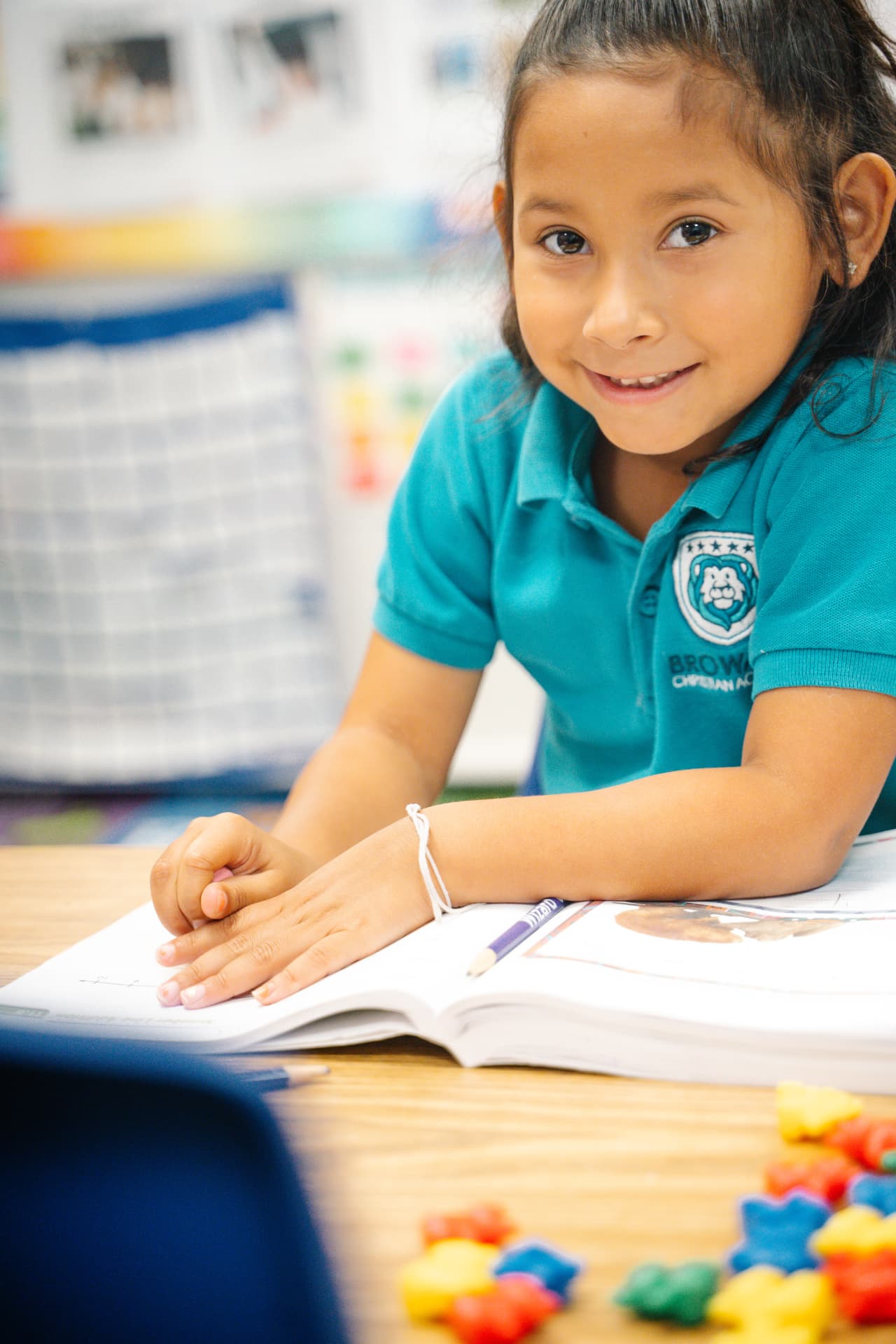 Student smiling at her desk while working in a workbook