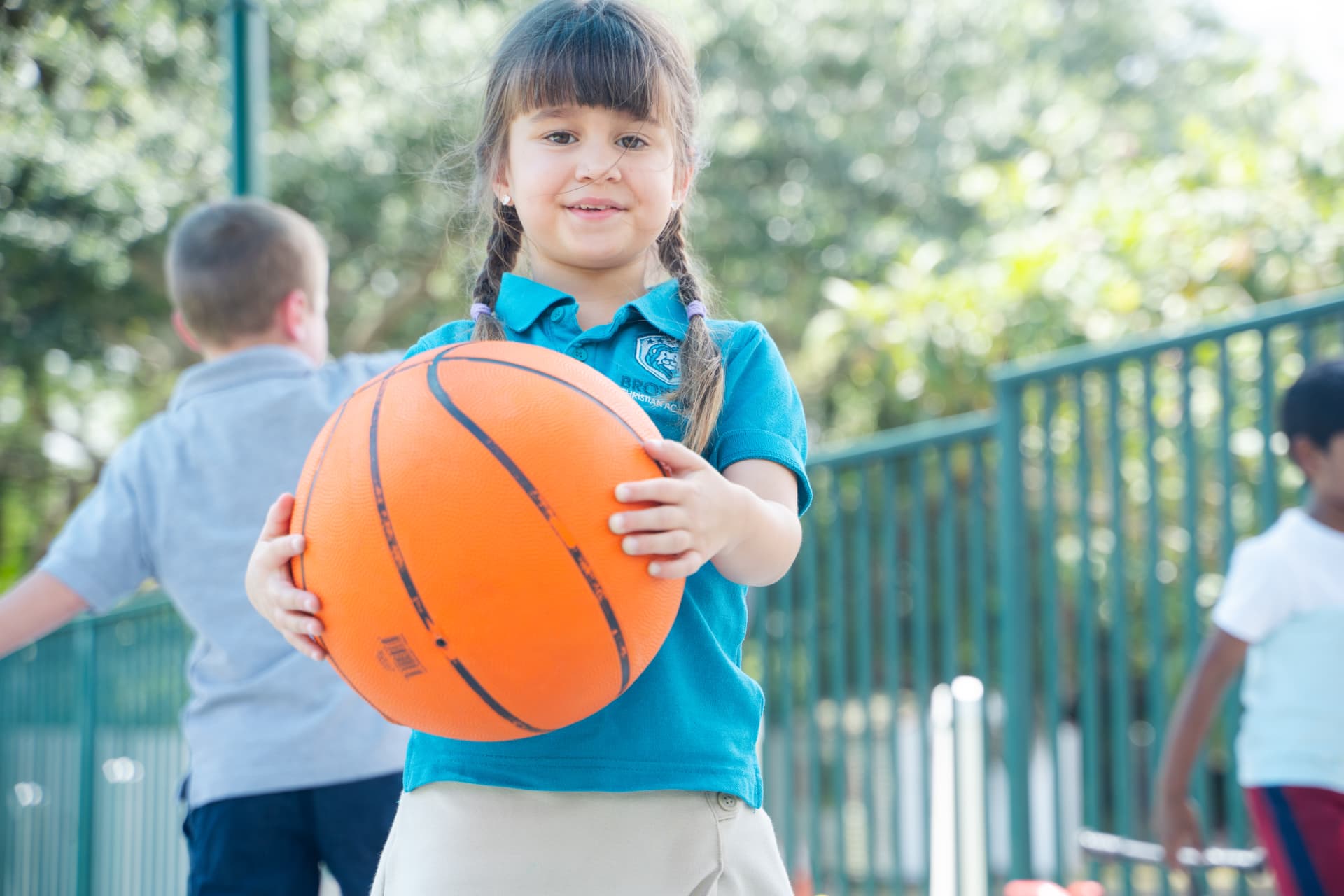 Student holding a basketball with classmates during recess