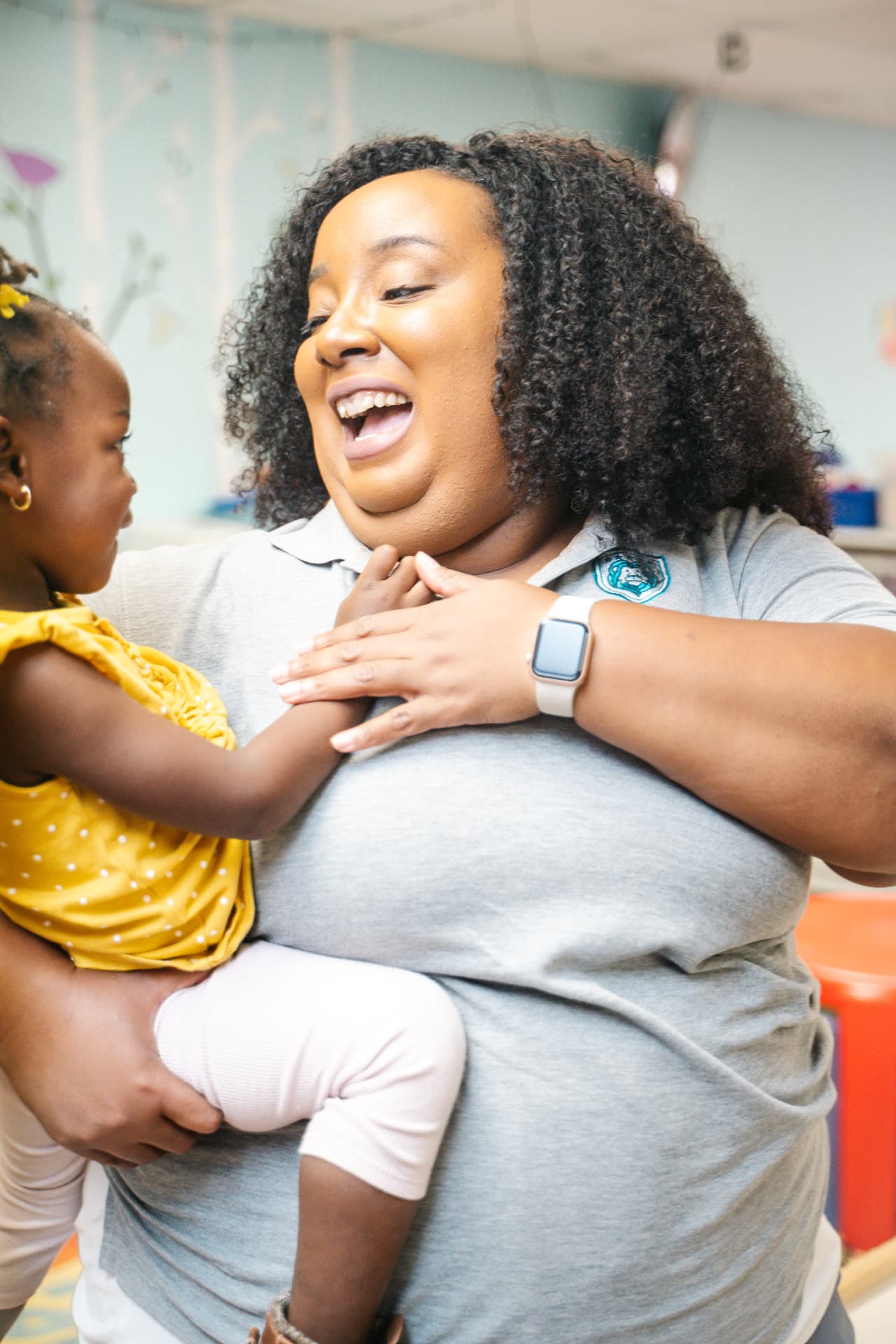 Early childhood teacher smiling with a toddler in the preschool classroom